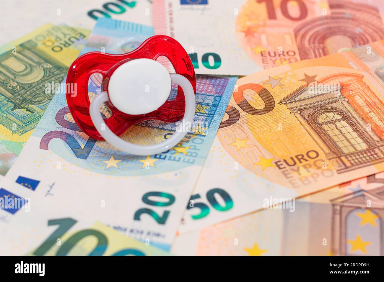 Childfree, Contraception and Birth Control Concept: Baby Pacifier on the Euro Banknotes. Having Children is Expensive and Unprofitable Stock Photo