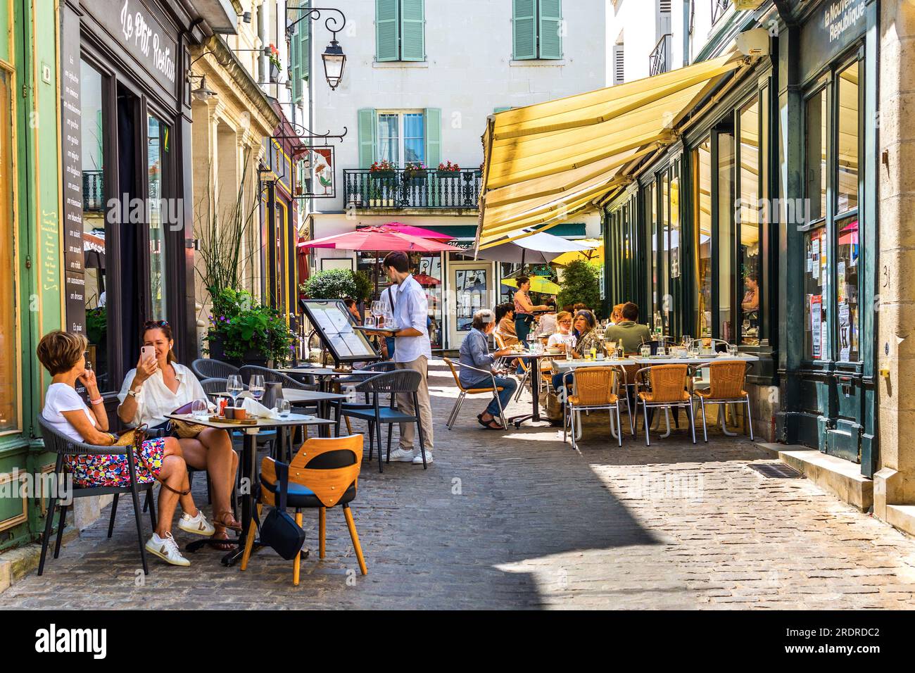Narrow city center cobbled street with terrace cafes and restaurants - Loches, Indre-et-Loire (37), France. Stock Photo