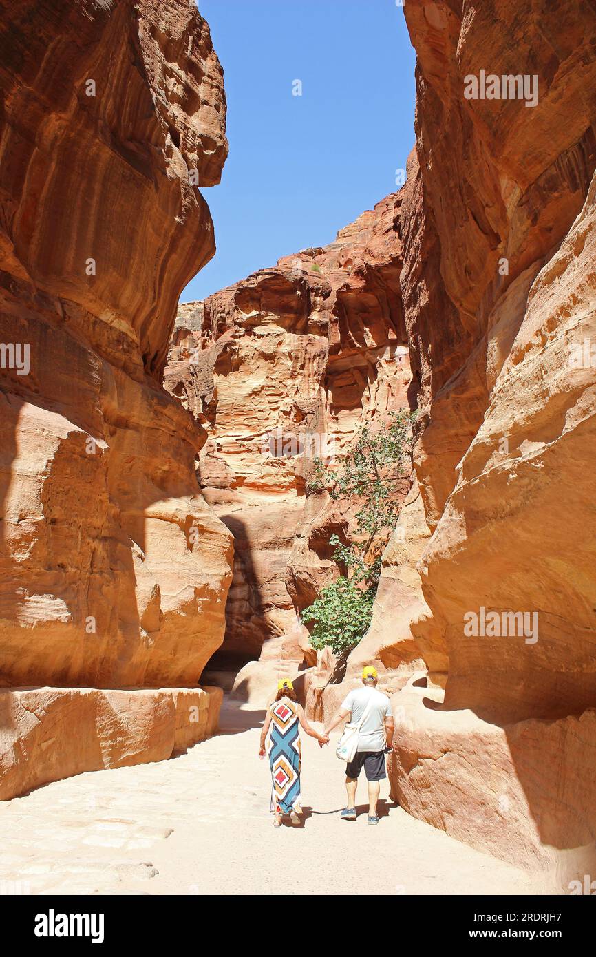 Senior couple walk hand in hand down Al-Siq towards the entrance to the ancient Nabatean City of Petra Stock Photo