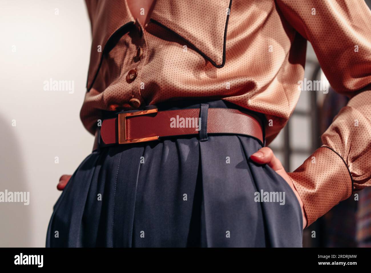 Female figure in a silky brown fancy blouse and dark blue pants with belt. Stylish clothing concept. Designer fashion collection Stock Photo