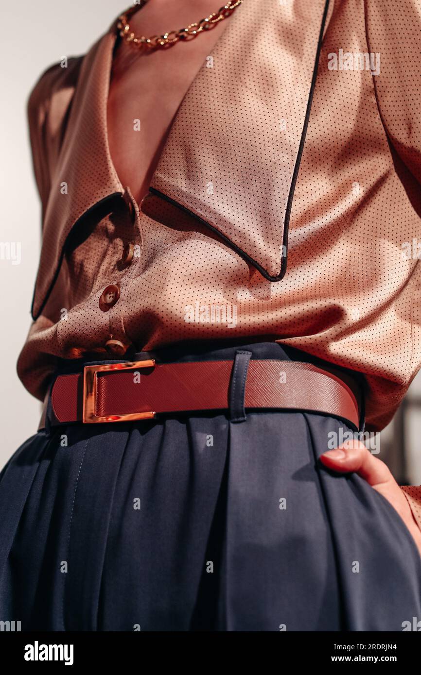 Female figure in a silky brown fancy blouse and dark blue pants with belt. Stylish clothing concept. Designer fashion collection Stock Photo