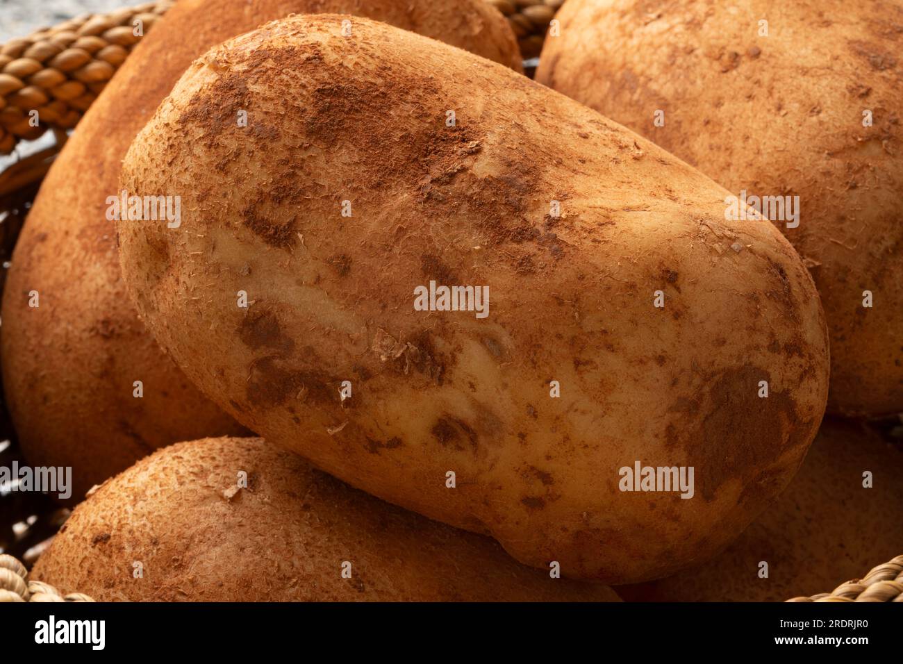 Fresh picked brown whole French potatoes with clay in a basket close up Stock Photo