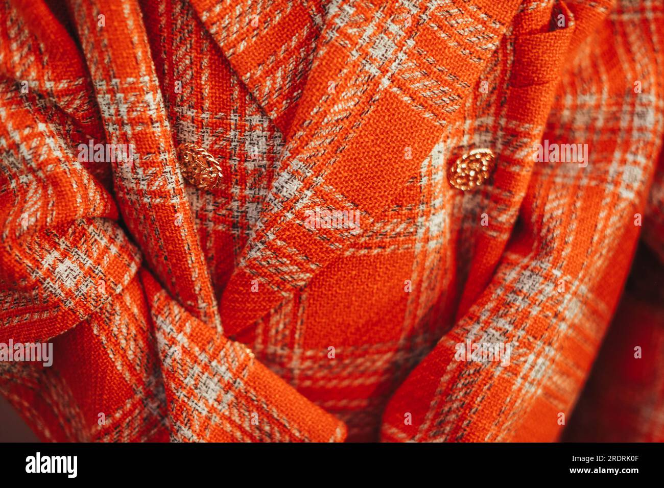 Close up details of a bright orange plaid women's jacket with golden buttons Stock Photo