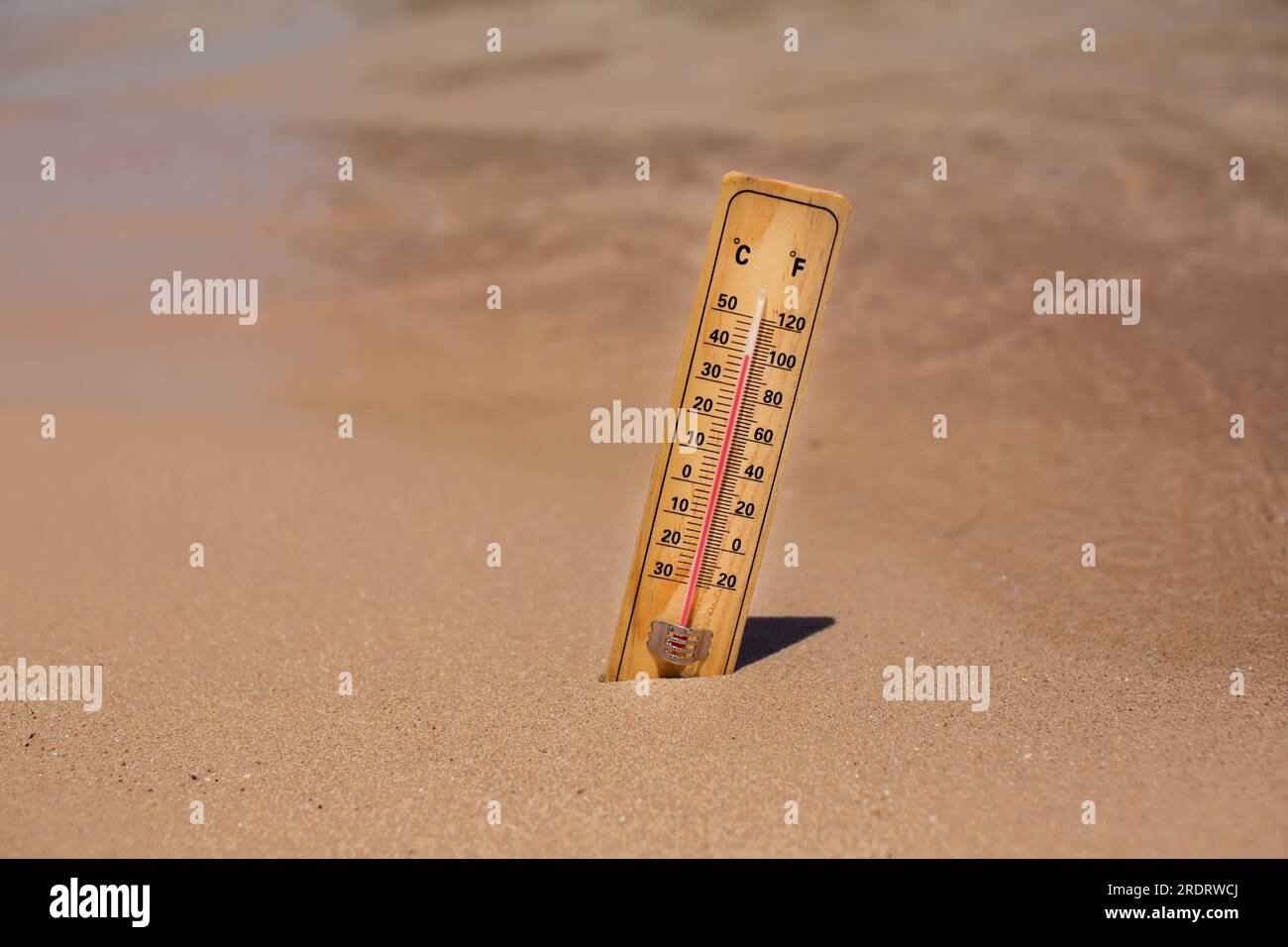 Thermometer on sand on a beach showing high temperature. Hot weather and climate concept Stock Photo