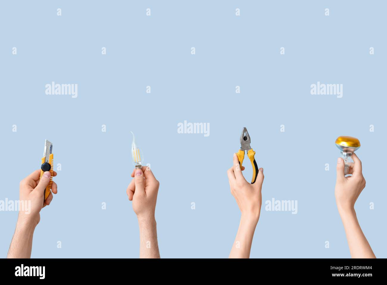 Electrician hands with light bulbs and tools on grey background Stock Photo