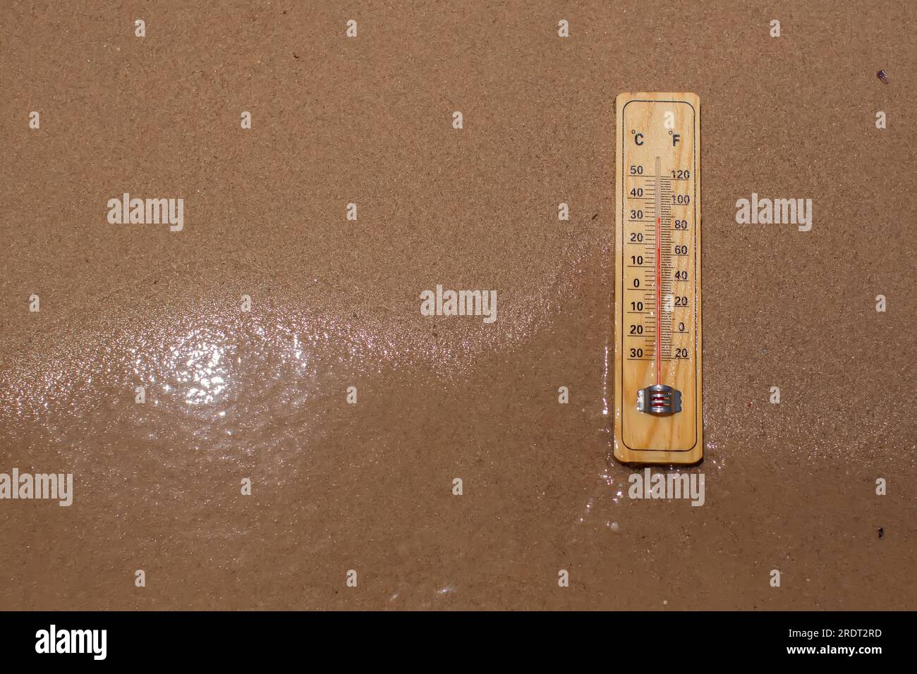 Thermometer on sand on a beach showing high temperature. Hot weather and climate concept Stock