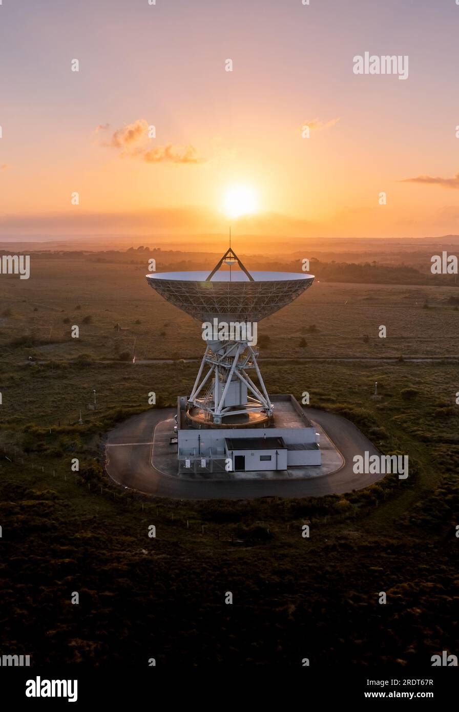 Aerial view of a satellite dish pointing upwards to the sky at sunset sending and receiving signals from deep space Stock Photo