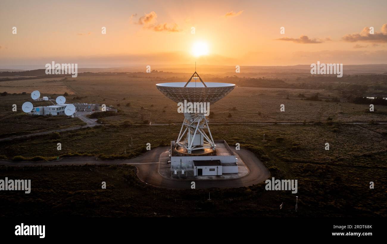 Aerial view of a satellite dish pointing upwards to the sky at sunset sending and receiving signals from satellites in deep space Stock Photo