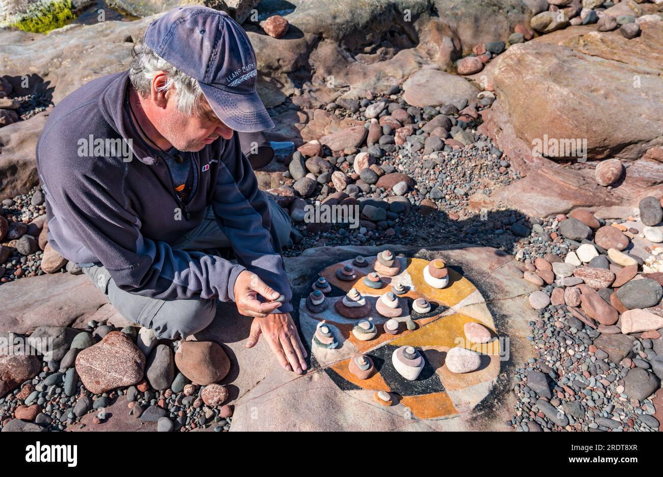 Man creating land art on beach, European Stone Stacking Championship