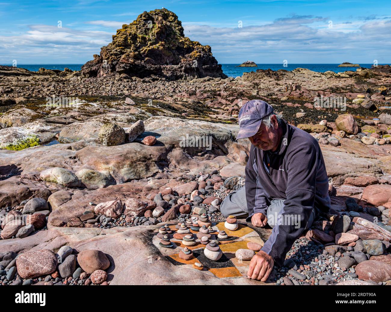 Man creating land art on beach, European Stone Stacking Championship