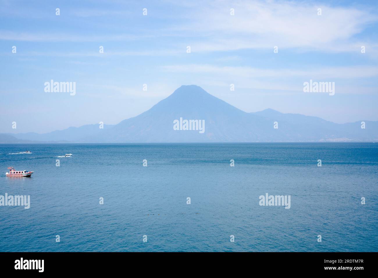 View of boats and volcano in the distance seen from the Lake Atitlan surface in Guatemala Stock Photo