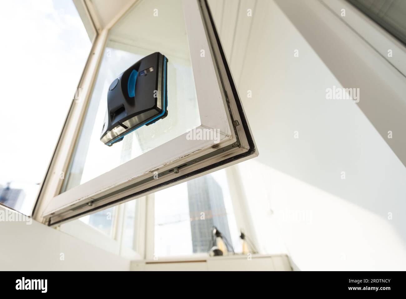 The white robotic window cleaner uses a brush and vacuum for a thorough