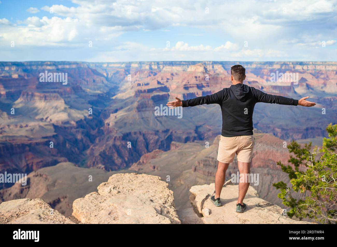 Young hiker is standing on a steep cliff taking in the amazing view ...