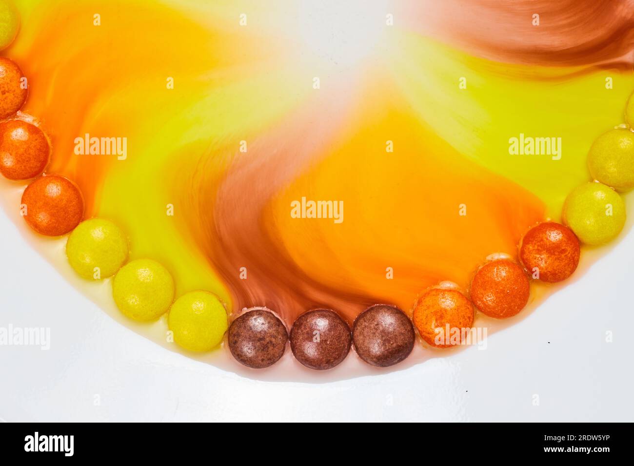 Water with color seeps into center of partial ring of colorful halloween candy Stock Photo
