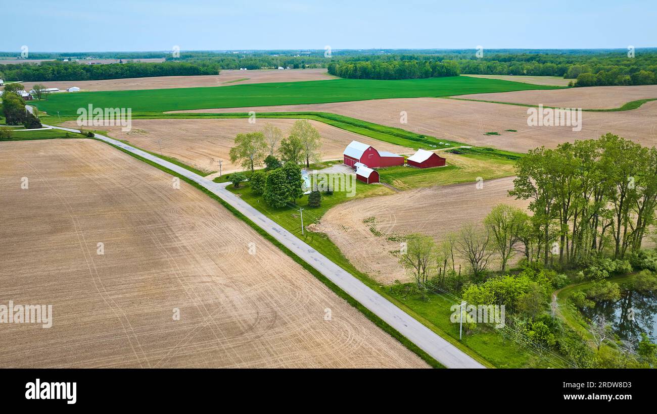 Aerial red farmhouse with barn, shed, lake side property small forest ...