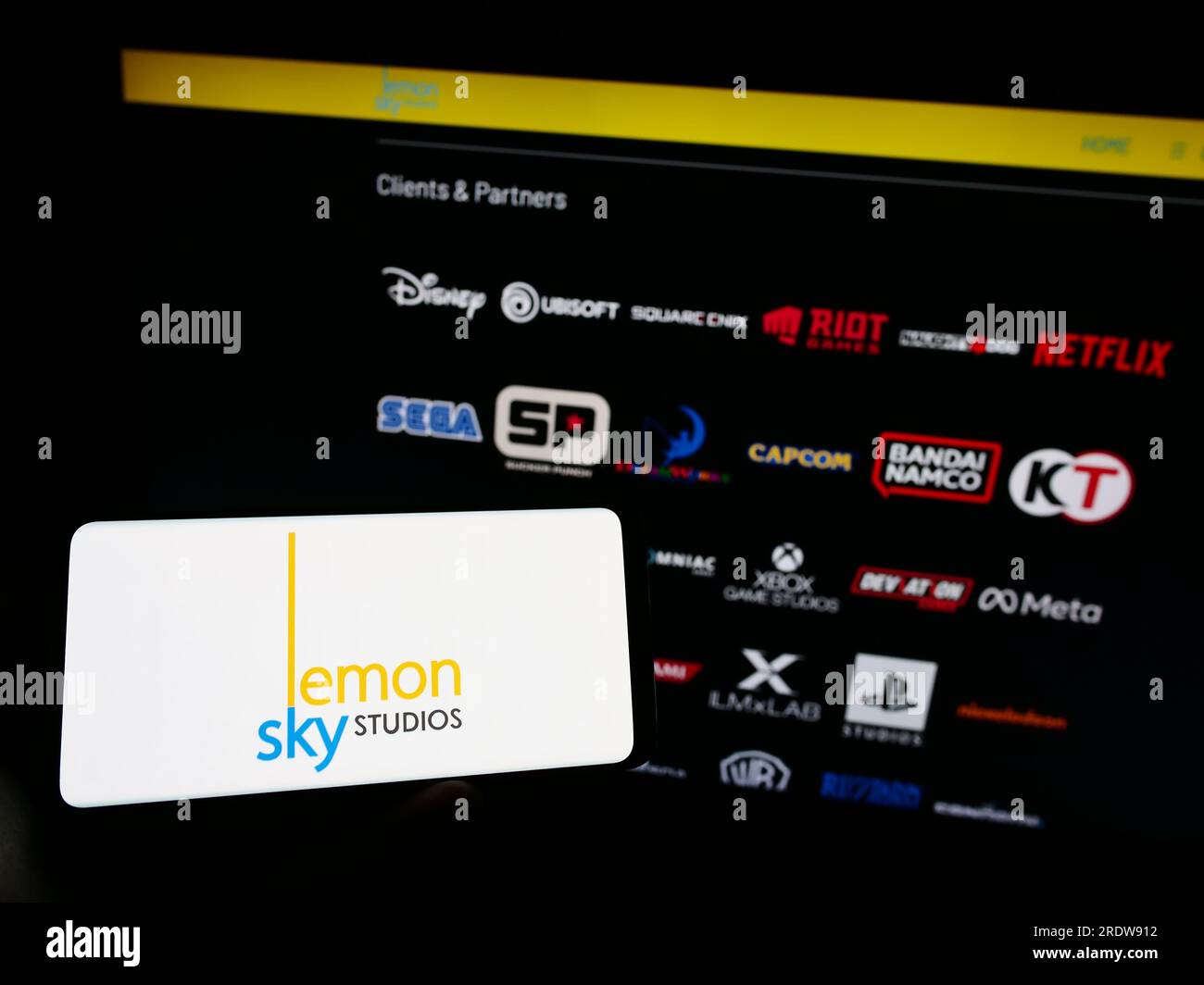 Person holding mobile phone with logo of Malaysian video games company Lemon Sky Studios on screen in front of web page. Focus on phone display. Stock Photo