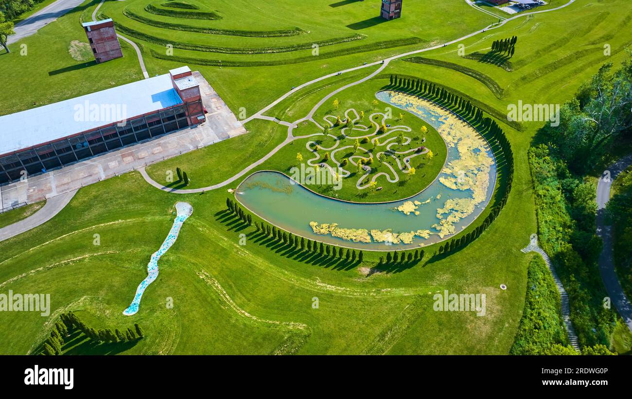Summertime aerial of Ariel Foundation Park over decaying factory and ...