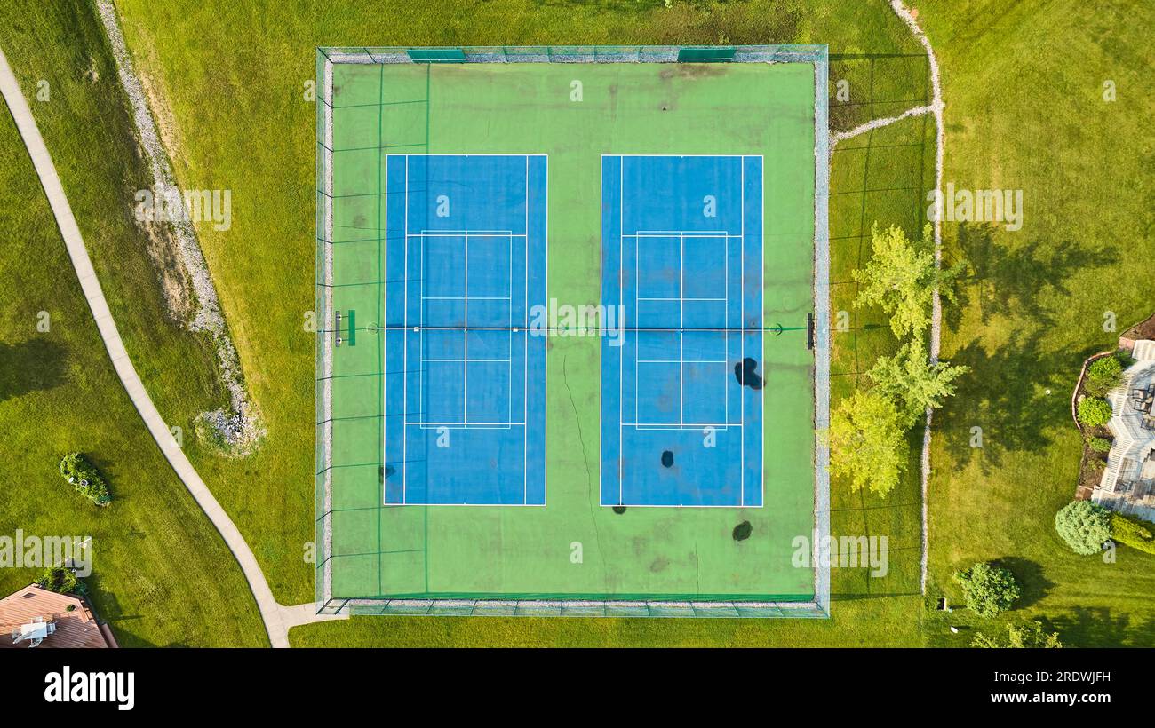 Neighborhood tennis court with blue and green playing field worn down