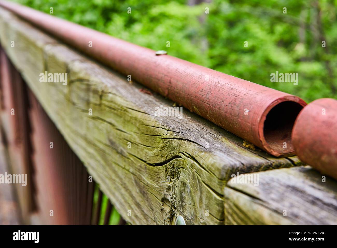 Long hollow red painted metal railing on top of weather worn green ...