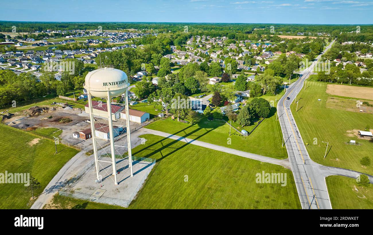 Aerial white Huntertown water tower on summer day with distant