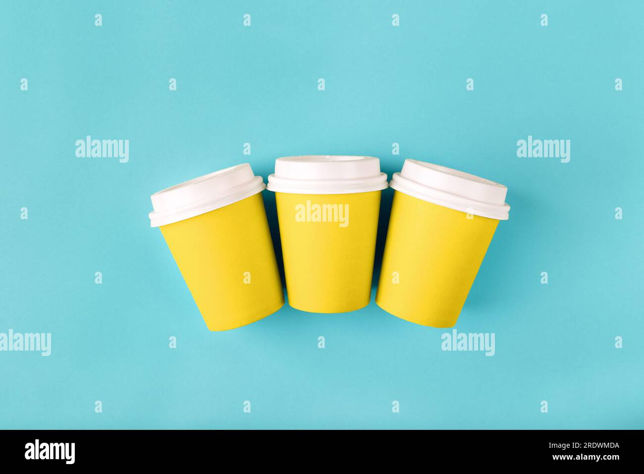 Three disposable paper yellow cups with close plastic lids for takeaway