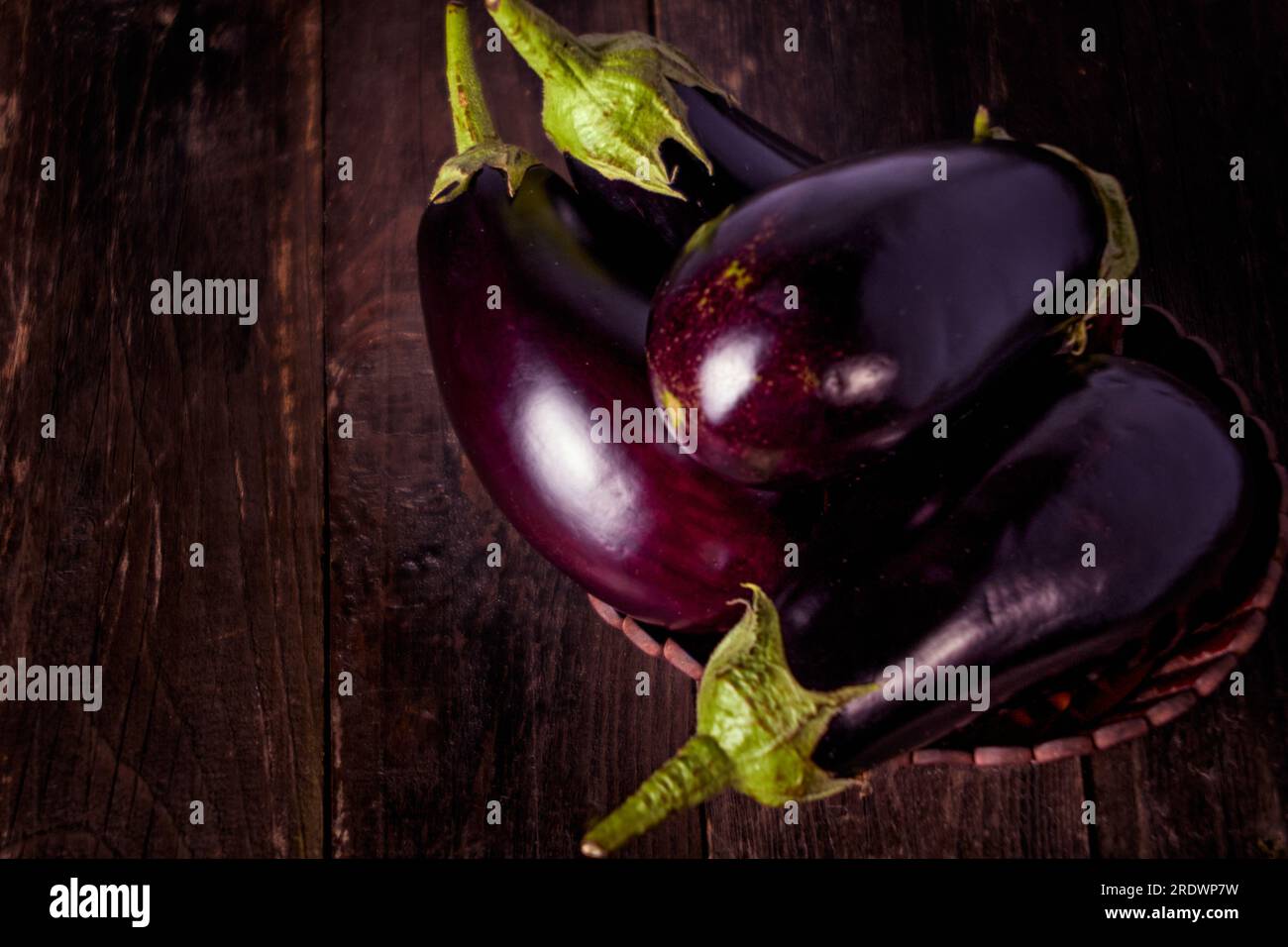 Close-up Several Eggplants On A Wooden Table in a Wooden Basket Stock Photo