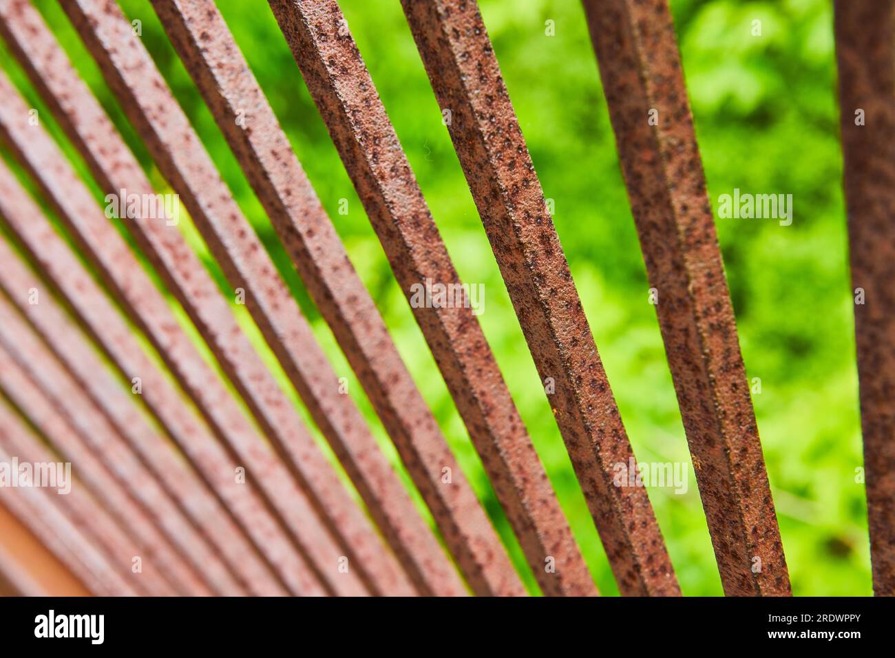 Rusting red and dark brown metal bars in fan formation with blurry ...