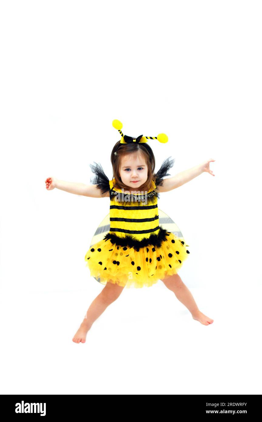 Little girl, dressed in bee costume, dances with her arms outstretched