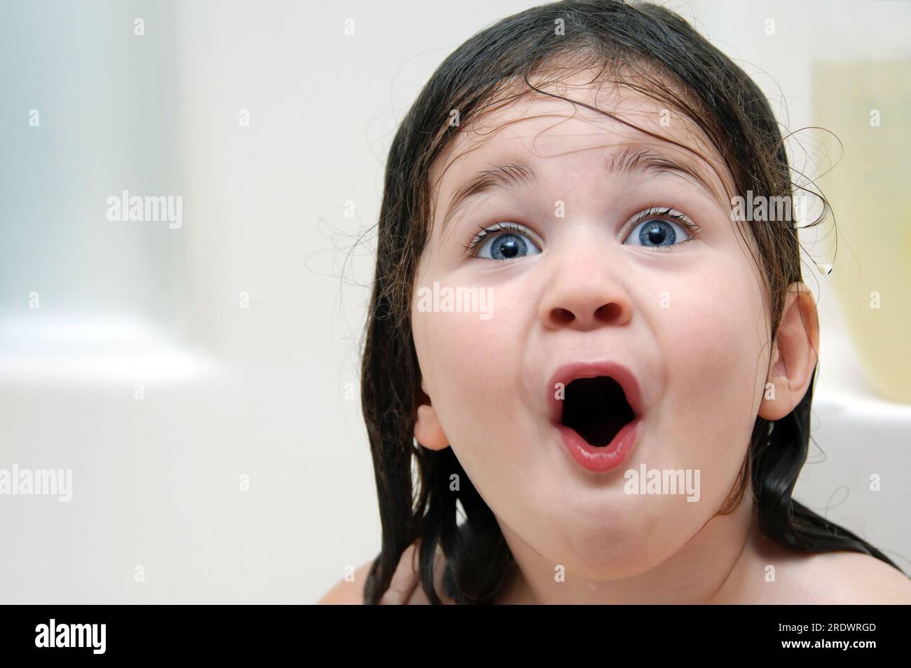 Little girl reacts to bathtime. Her mouth is open in amazement and her hair is soaking wet Stock