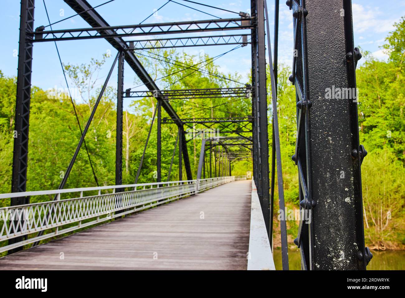 Black metal beams, rivets in iron bridge poles, wooden flooring over
