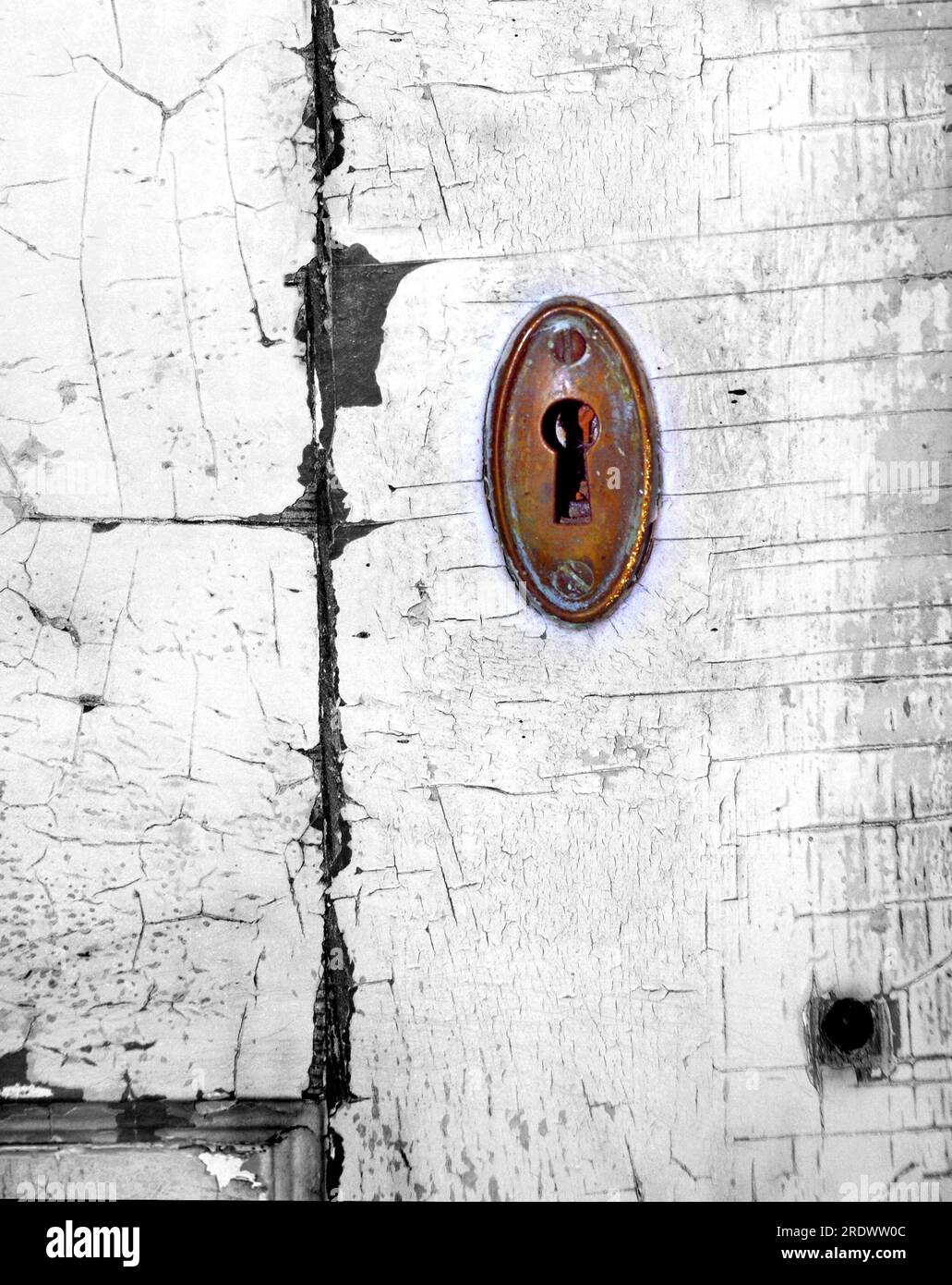 Colorized image of an antique keyhole.  Door facing is cracked and paint peeling.  Keyhole is brass and in need of a good polish. Stock Photo
