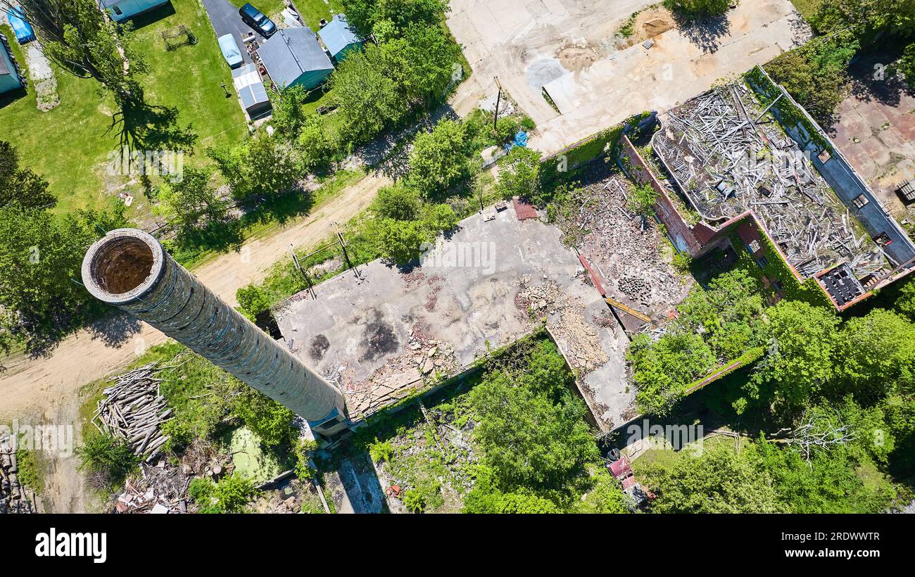 Old abandoned decaying crumbling building, icy walls, smokestack, silo summer ivy green aerial Stock Photo