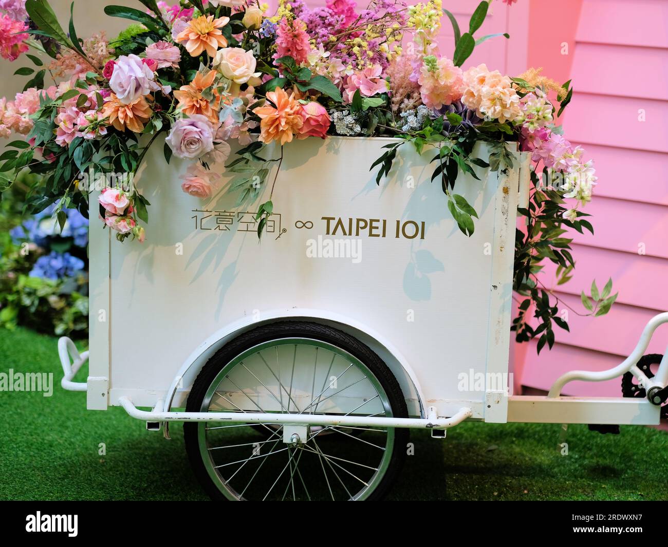 A metal cart attached to a bicycle with artificial flowers decorating a courtyard at Taipei 101 shopping center and mall; Taipei, Taiwan. Stock Photo