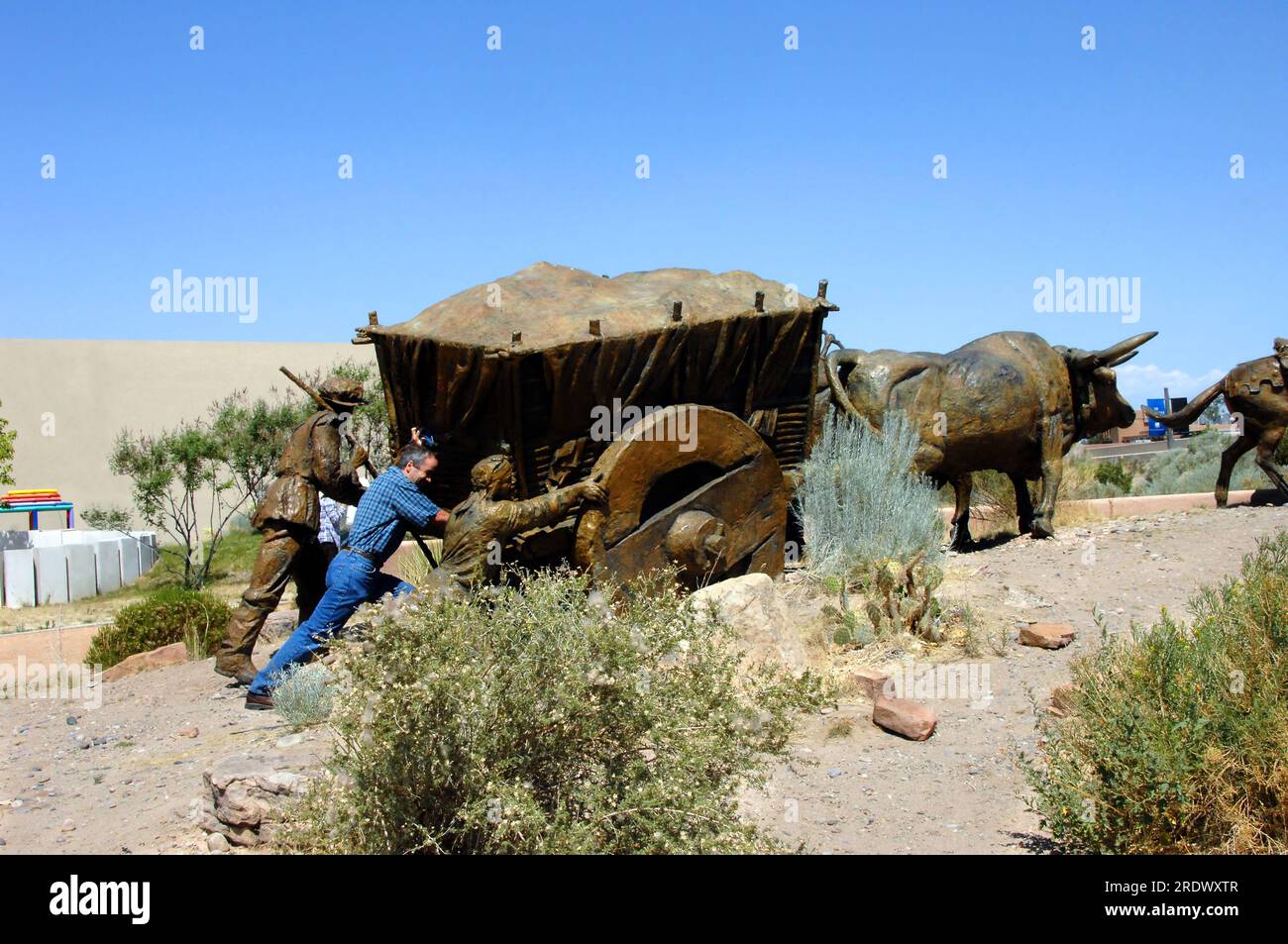 Tourist visiting the Albuquerque Museum of Art does his best to help the early settlers as they carried a very heavy load across New Mexico. Stock Photo