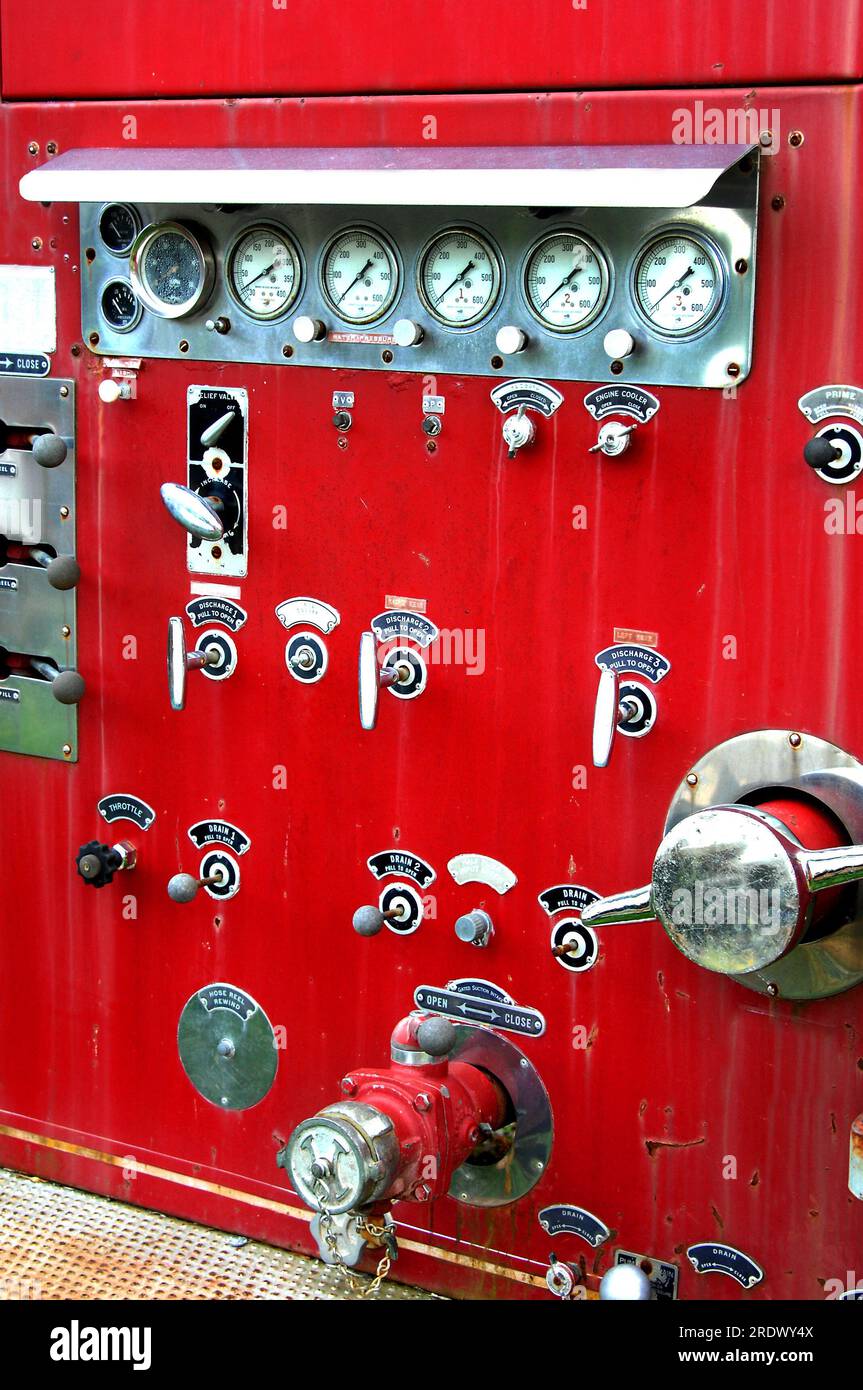 Controls on an antique fire engine are faded and worn. Red paint is scratched and fading Stock
