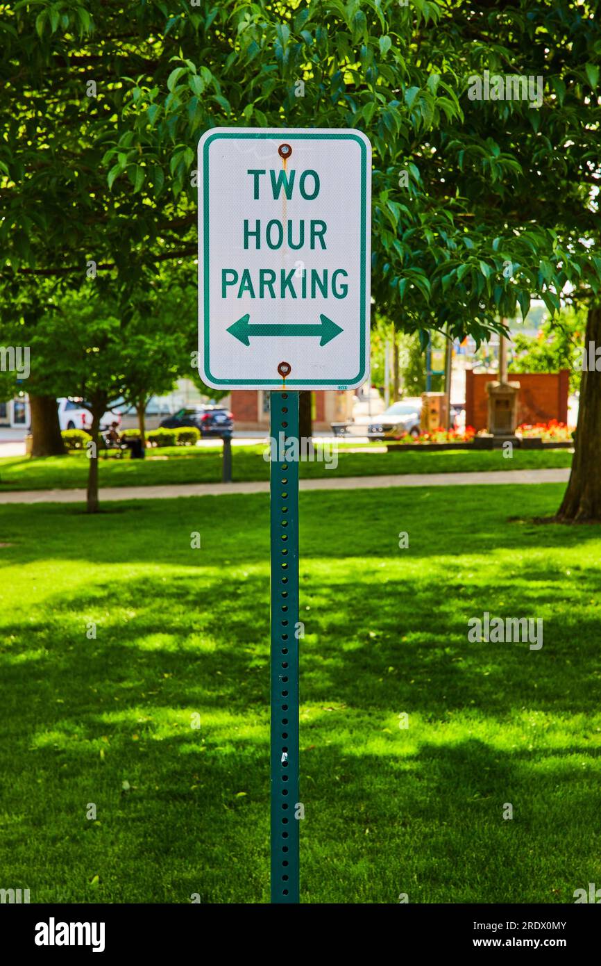 Green Two Hour Parking sign in front of park in summertime Stock Photo