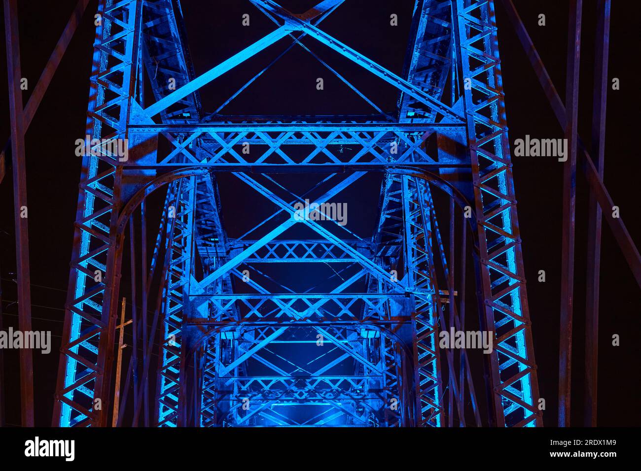 Blue neon lights illuminating upward truss crossing beams of railroad