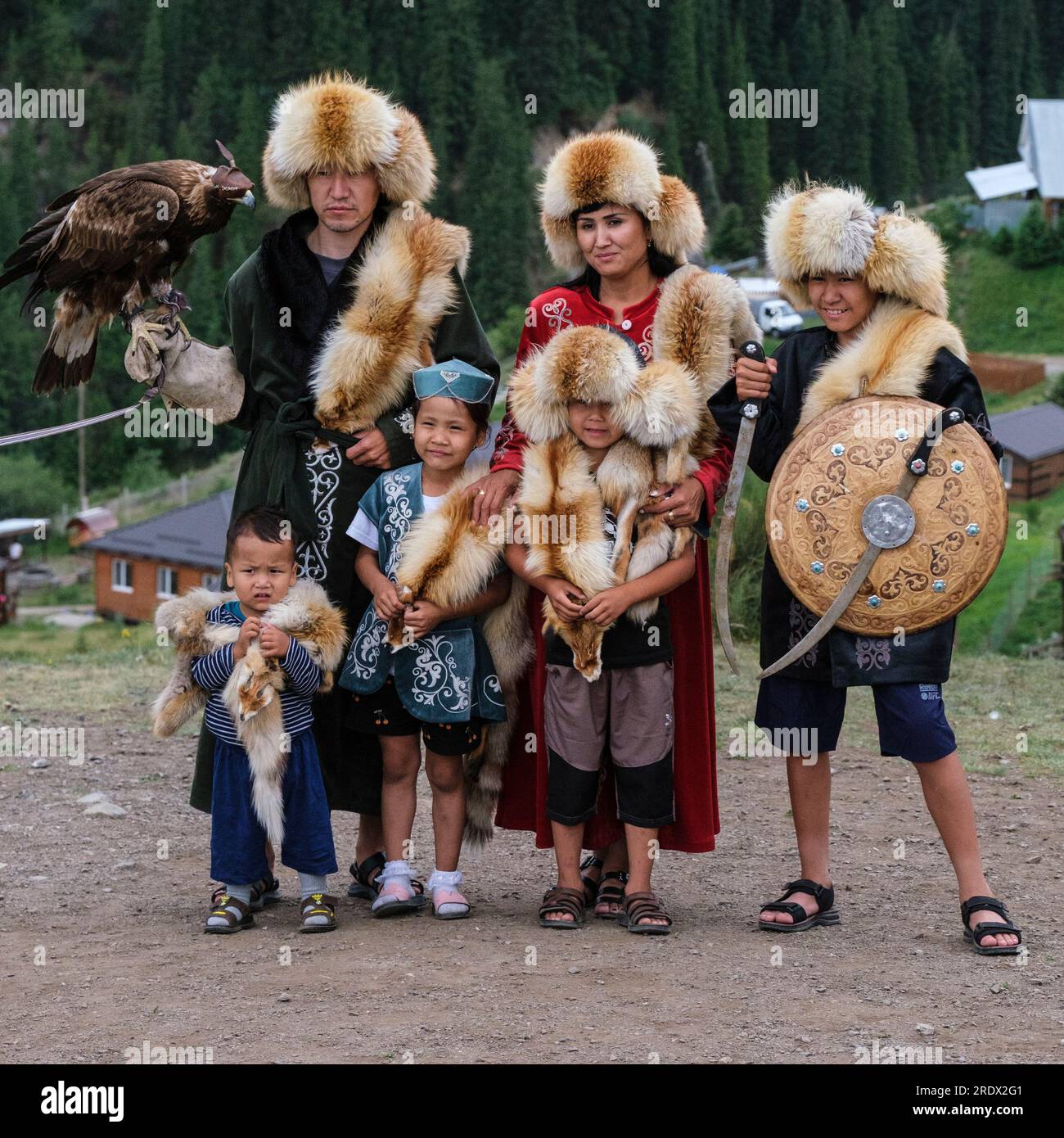Kazakhstan, Kolsay Lakes National Park. Family Posing for Photo in Traditional Costume with Hooded Falcon. Stock Photo