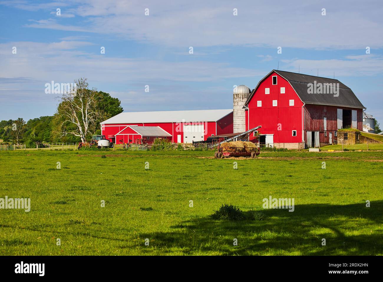 Red barn on farmland with hay bales on feeder in summer Stock Photo - Alamy
