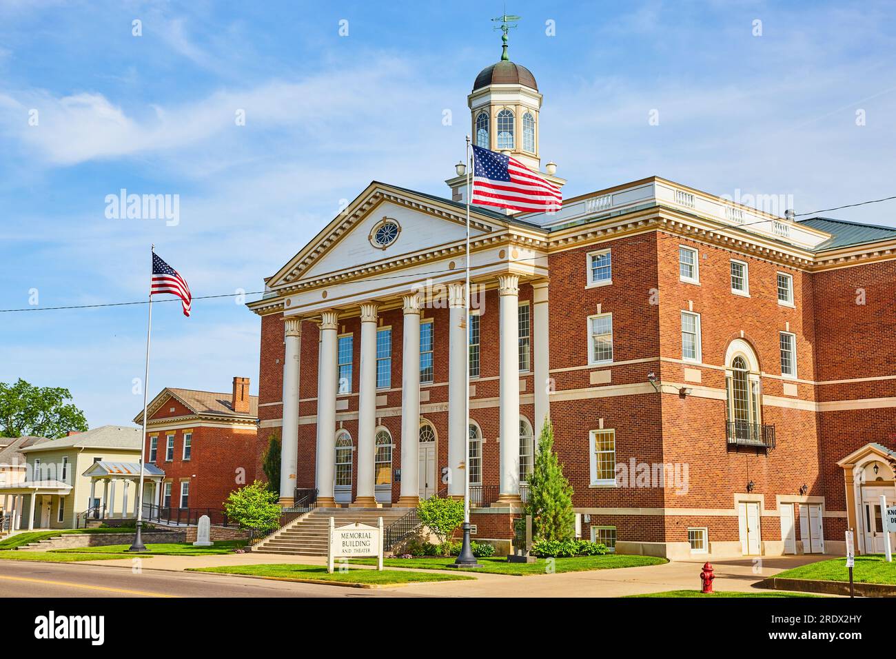 Red brick building with wind vane and American flags out front Stock ...