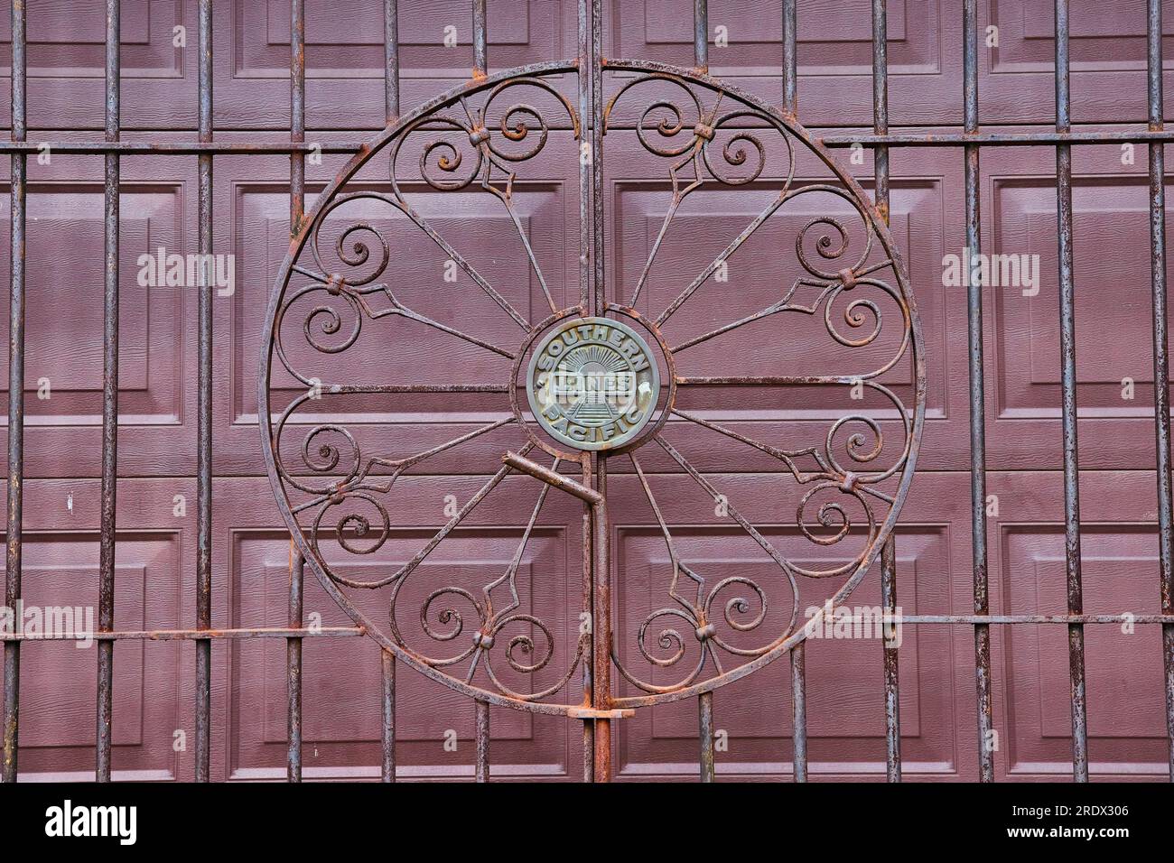 Southern Pacific lines rusty metal gate in front of maroon garage doors