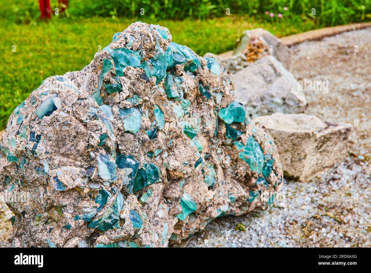 Turquoise blue and sapphire glass embedded and fused to destroyed concrete rock with glassy ground Stock Photo