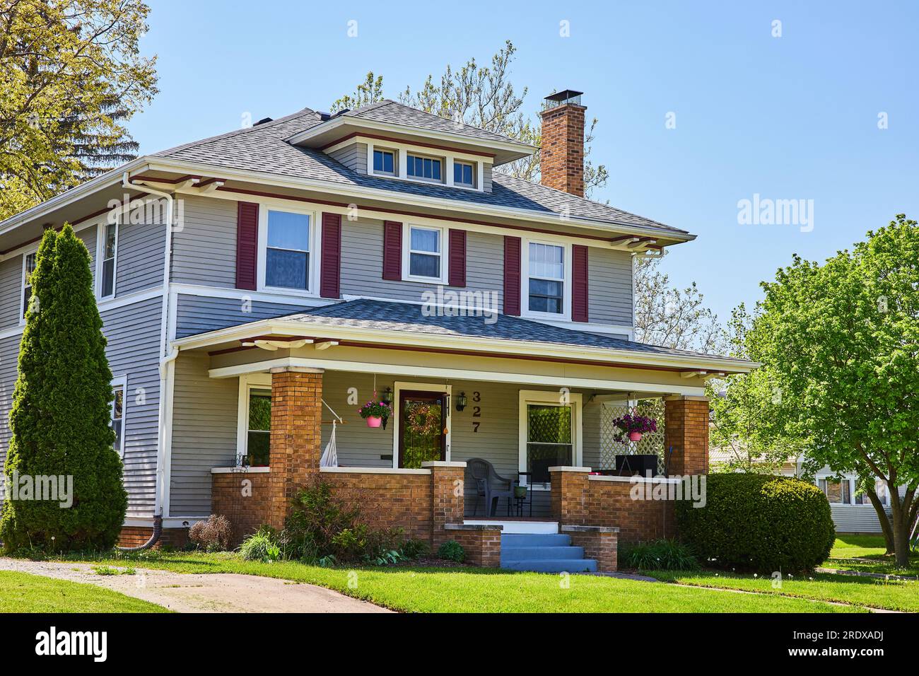 Front of twostory house, summer landscaping, brick porch patio, gray