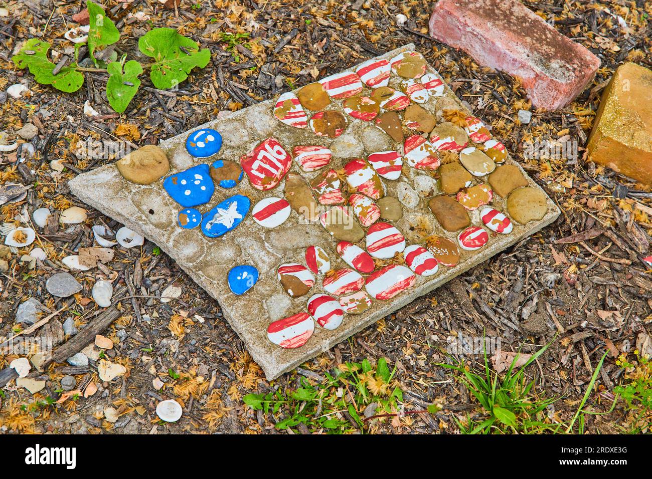 Busted concrete plaque with painted stones arranged in American flag ...