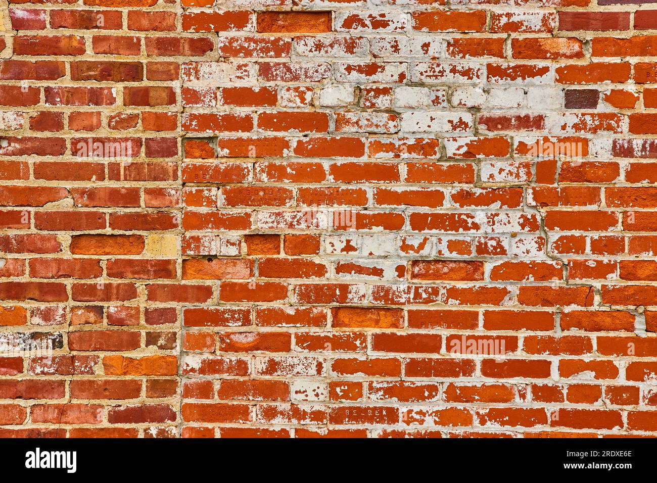 Wall of red bricks with unusual seem joining faded bricks with bright orange bricks Stock Photo