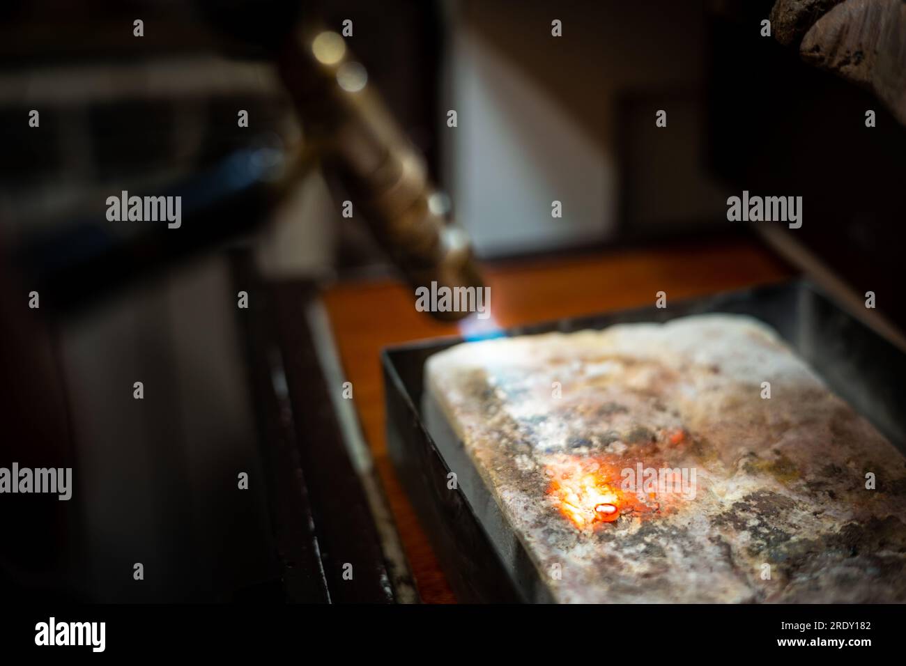 Jeweler melting silver metal with open flame blow torch welding