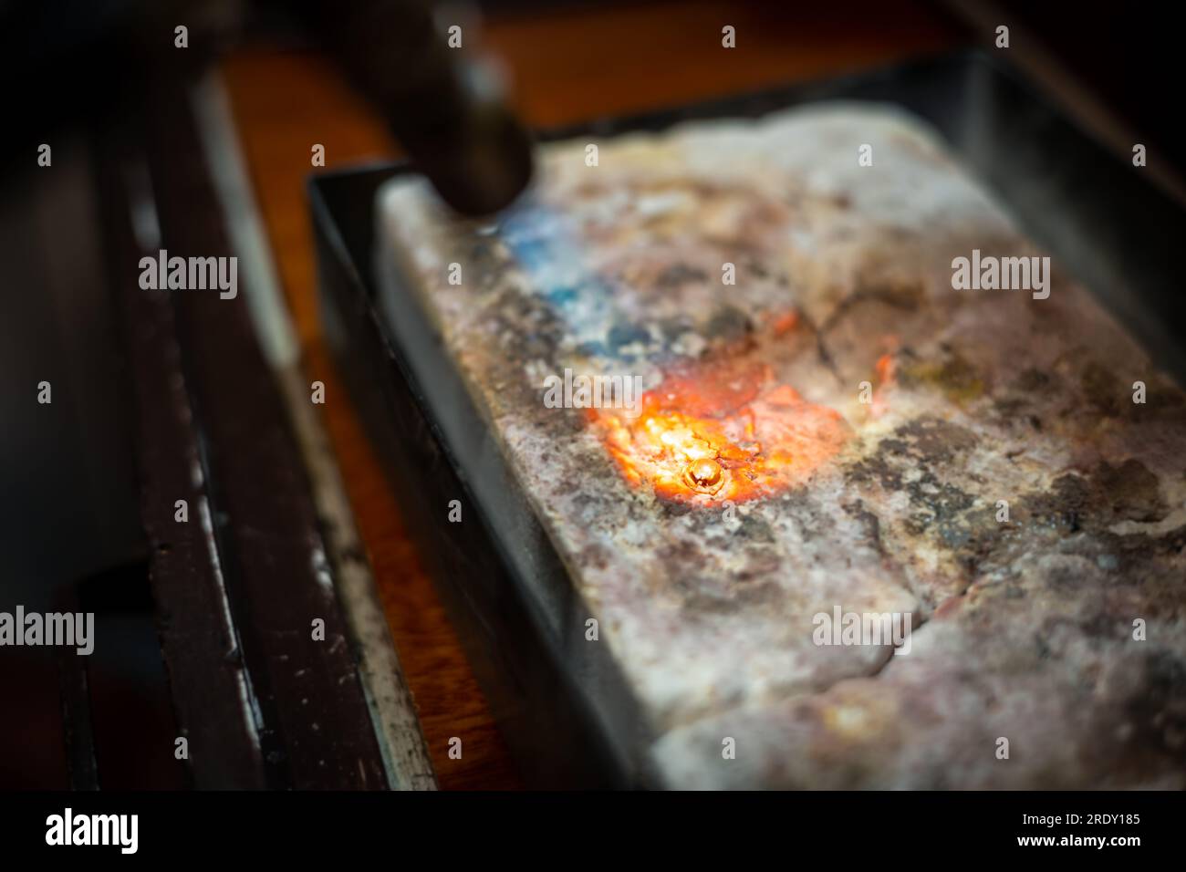 Jeweler melting silver metal with open flame blow torch welding