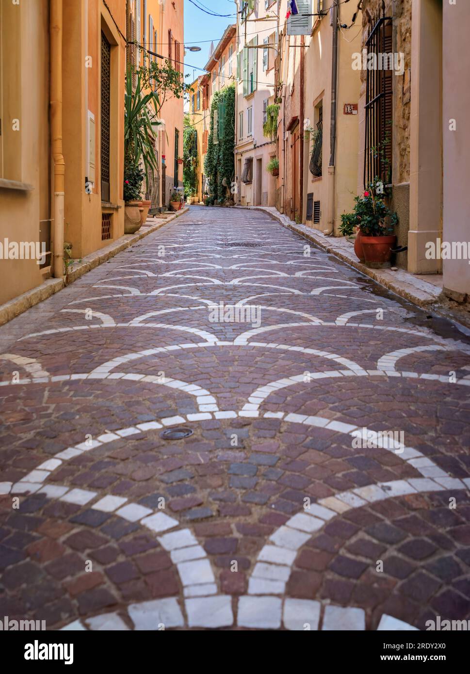 Ornate mosaic street pavement between traditional old houses near the covered provencal farmers market in old town or Vieil Antibes, South of France Stock Photo