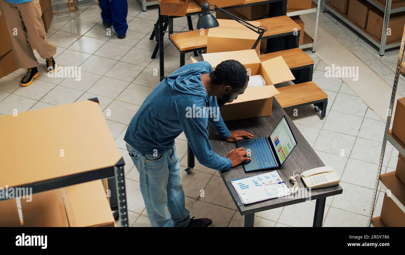 African american employee putting products in cardboard boxes, working ...