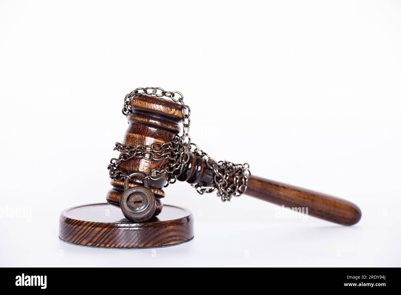 The judge's gavel is tied with a chain to the padlock on white background , not the legality of the sentence and the arrest of the judge Stock Photo